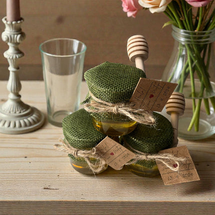 Green wrapped items with tags on a wooden surface, next to a vase of flowers and glassware.